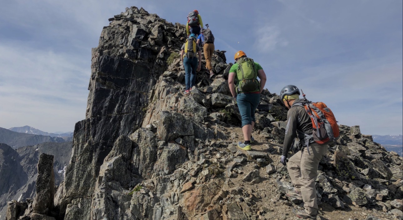 Hikers scrambling along a mountain ridge